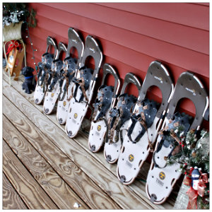 A lineup of snowshoes along a red wall of a house