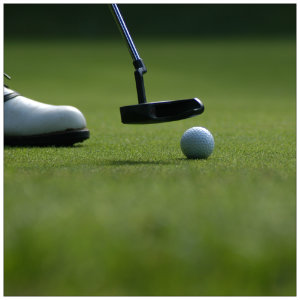 Golfer on a putting green with a putter next to a white golf ball 