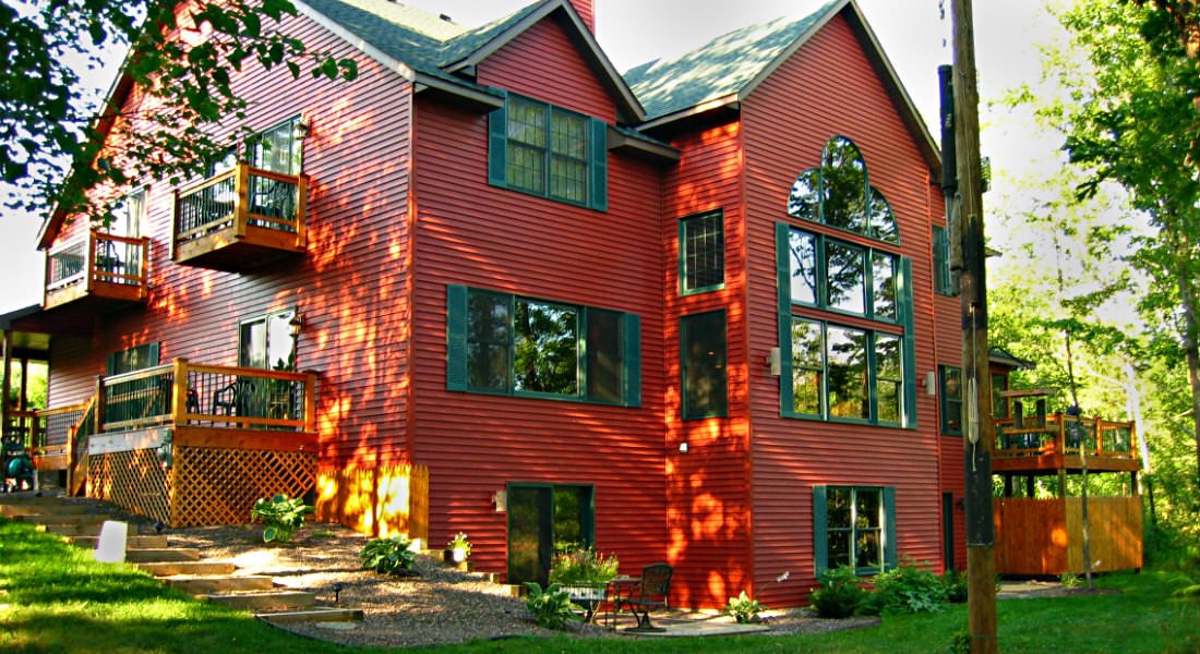 Close of view of exterior of main lodge painted in red, with blue-green shutters and pine balconies.